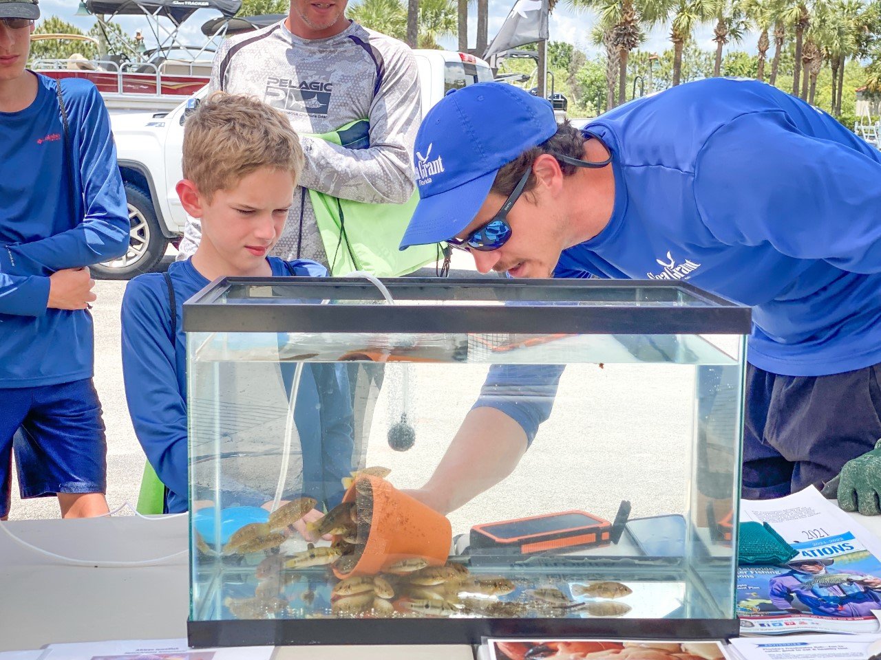 Mike Sipos, Florida Sea Grant Agent teaches a junior angler about African jewelfish, a common invasive cichlid species found in Southwest Florida, during the 2022 roundup.